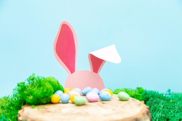 El conejo rosa se esconde detrás de un trozo de tarjeta de felicitación de Pascua con símbolos de Pascua