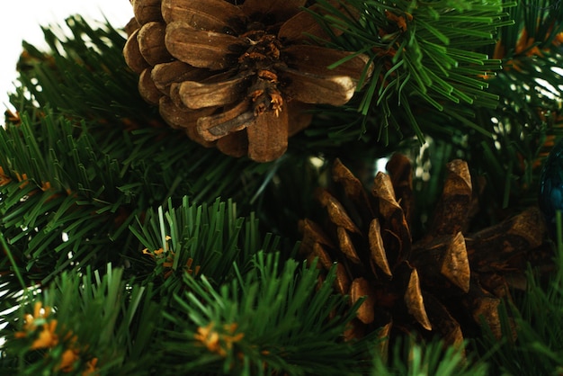 Cones de Natal no fundo de galhos e agulhas de uma árvore de Natal artificial, close-up