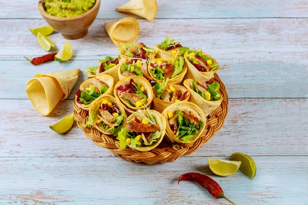 Cones de tortilha recheados com fajita na cesta de vime com limão e guacamole