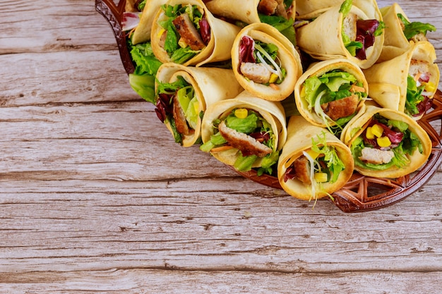 Cones de tortilhas mexicanas cheias de carne, milho e salada na mesa de madeira.