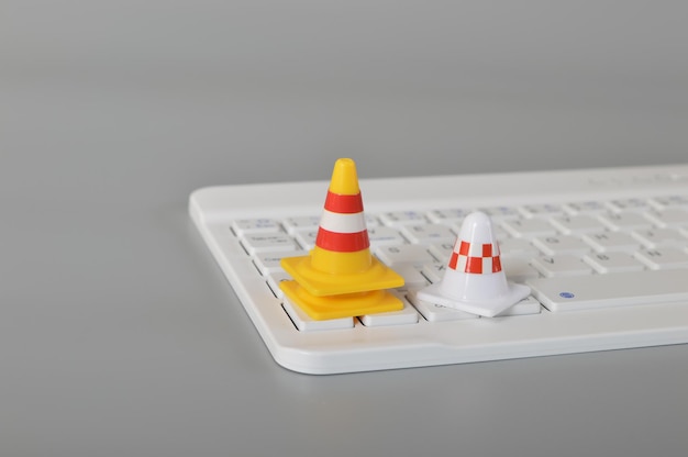 Foto cones de tráfego e teclado de laptopsistema de computador em conceito de reparo e manutenção de construção