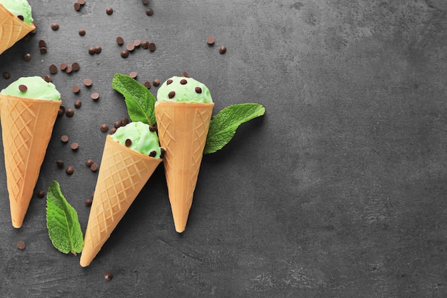 Cones de waffle com delicioso sorvete de chocolate com menta e folhas frescas em fundo escuro