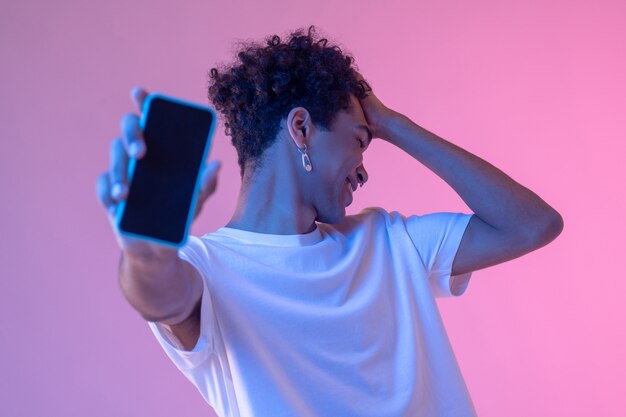 Conexão. Foto de um cara sorridente de cabelos cacheados com um smartphone