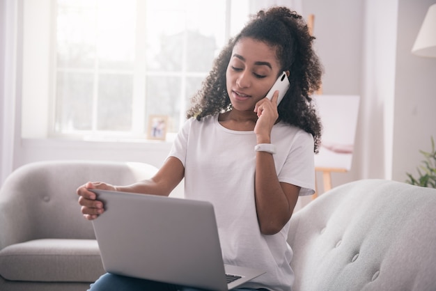 Conexão móvel. Mulher agradável e agradável falando ao telefone enquanto faz um pedido