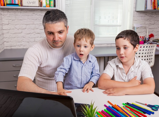 Conexión con la familia a través de una videollamada. Familia haciendo videollamadas con amigos o familiares. Hombre con niños sentados en casa y con videollamada. Concepto de tecnología, familia, conexión, paternidad.