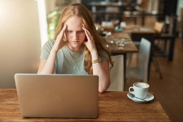 Una conexión lenta arruinará tu día Captura recortada de una mujer joven que parece estresada mientras está sentada frente a su computadora portátil