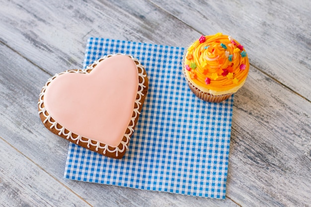 Confeitaria de bolinho de coração e cupcake de laranja em doces de guardanapo e bons sentimentos, parabéns ...