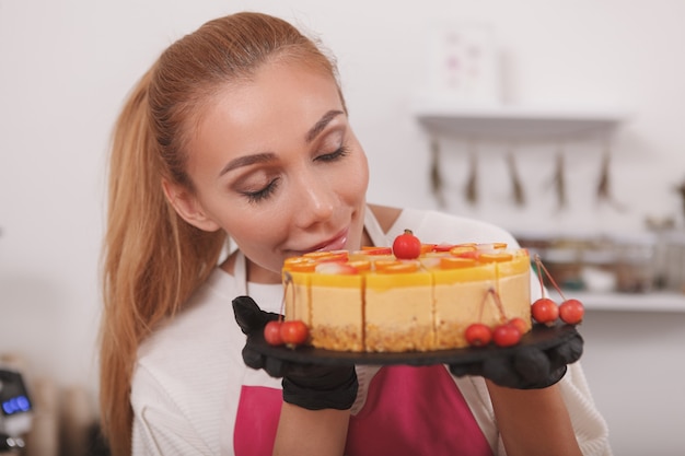 Confeiteira cheirando um delicioso bolo de manga cru que ela está vendendo em seu café