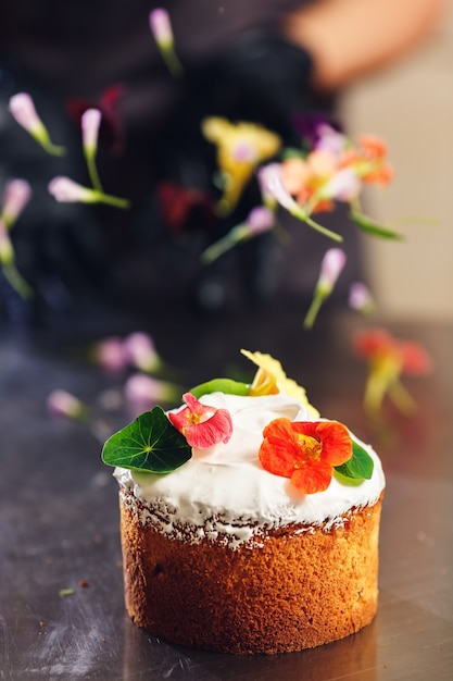 Confeiteiro decora o bolo da páscoa com flores delicadas.