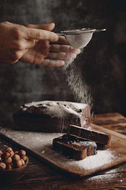 Confeiteiro polvilha brownie de chocolate em pó com açúcar de confeiteiro