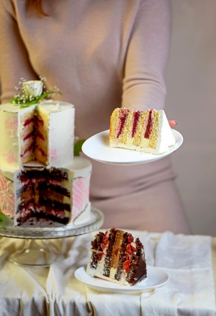 Confeiteiro prepara cortes e serve um bolo de casamento festivo de duas camadas decorado com flores frescas em um fundo cinza