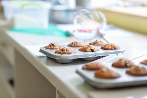 Confeiteiro tirou muffins recém-assados em uma assadeira em cima da mesa do forno