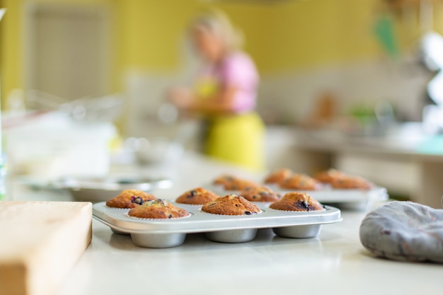 Confeiteiro tirou muffins recém-assados em uma assadeira em cima da mesa do forno