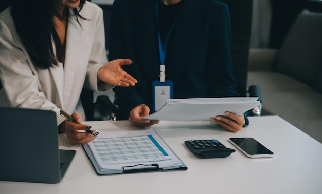 Conferência de cooperação Reunião da equipa de negócios Colegas investidores presentes a discutir novos dados de gráficos financeiros do plano na mesa do escritório com portátil e tablet digital Contabilidade financeira investimento