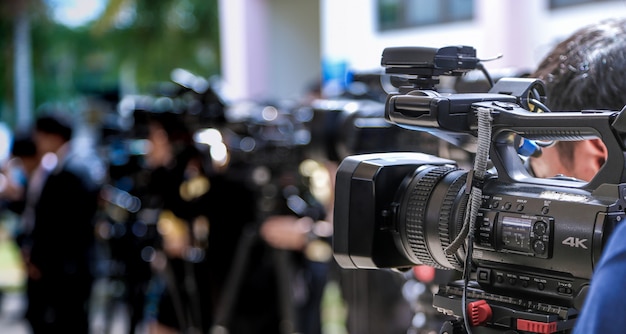 Foto conferência de imprensa. close-up da câmera de vídeo no grupo borrado de imprensa e fotógrafo de mídia