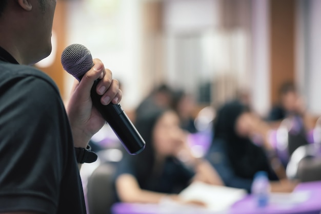 El conferenciante del hombre de cerca habla con el micrófono en foco selectivo.