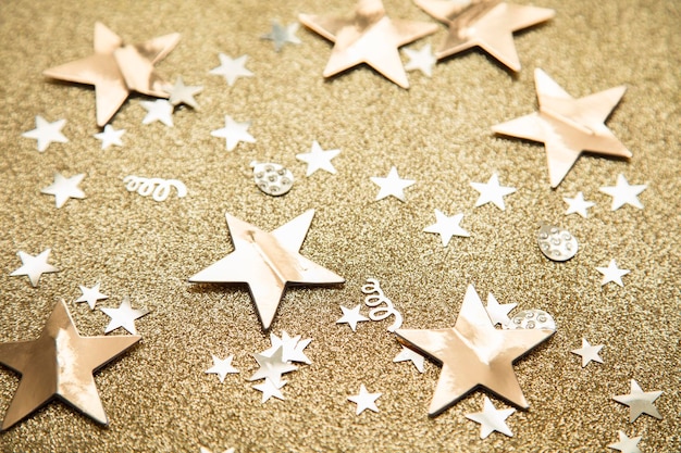 Confete de festa de brilho de estrela dourada em um fundo de glitter dourado