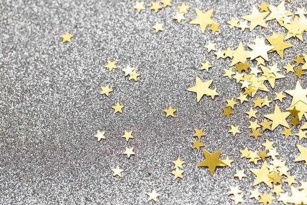 Foto confete estrela de ouro em um fundo de brilho prateado fundo festivo de férias