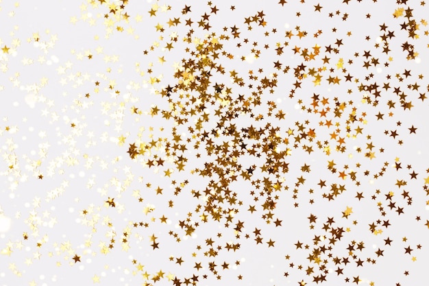 Confetes de estrelas coloridas de ouro brilhante em um fundo branco