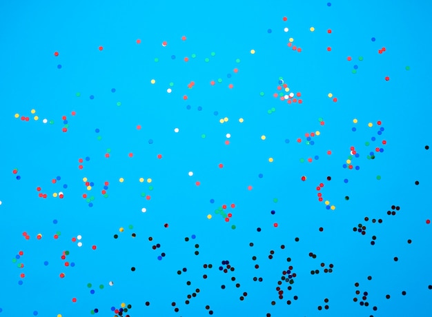 Foto confetes redondos multicoloridos brilhantes espalhados sobre um fundo azul