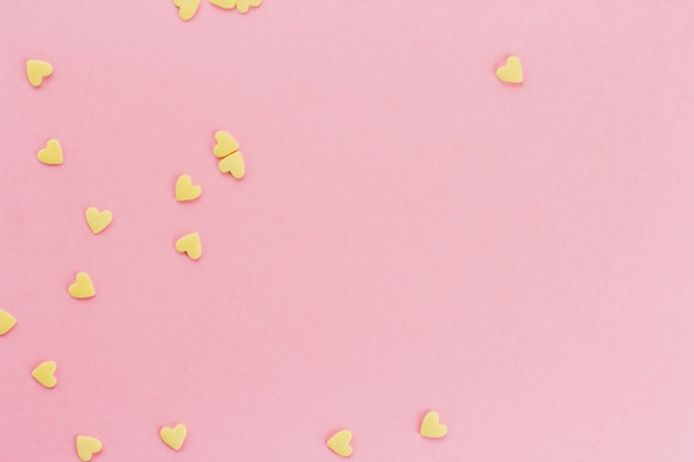 confeti amarillo en forma de corazones sobre un fondo rosa espacio de copia