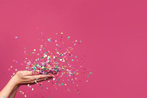 Confeti cayendo sobre un fondo rosado brillante
