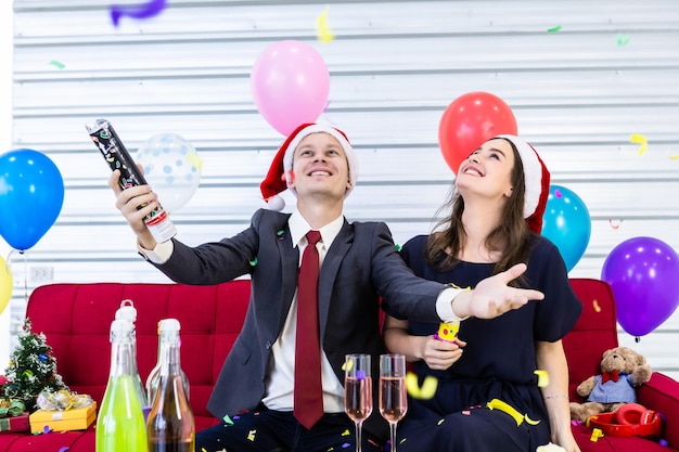 Foto confeti cayendo sobre una pareja sentada en casa durante la navidad