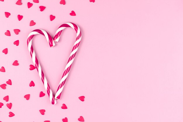 Foto confeti de confitería rojo o rosa en forma de corazones y bastones de caramelo