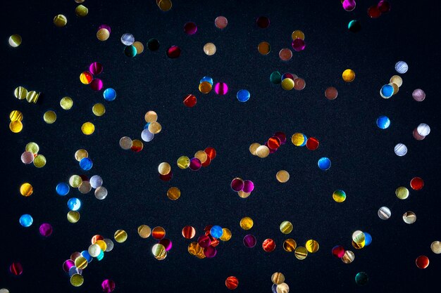 Foto confeti dorado de colores de gran tamaño sobre fondo negro telón de fondo festivo de chispas para cumpleaños