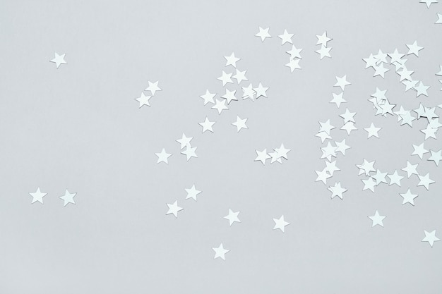 Foto confeti de estrellas plateadas en fondo gris de navidad o fondo festivo de invierno