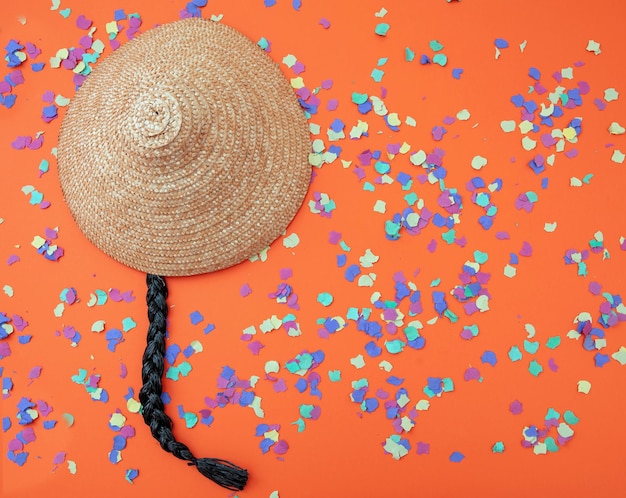 Confeti de pelo trenzado de sombrero chino de fiesta de carnaval sobre fondo naranja Plantilla de anuncio Vista aérea