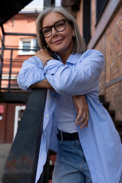 Confiada anciana madura con cabello gris vestida con estilo camina por la ciudad y se detuvo en el