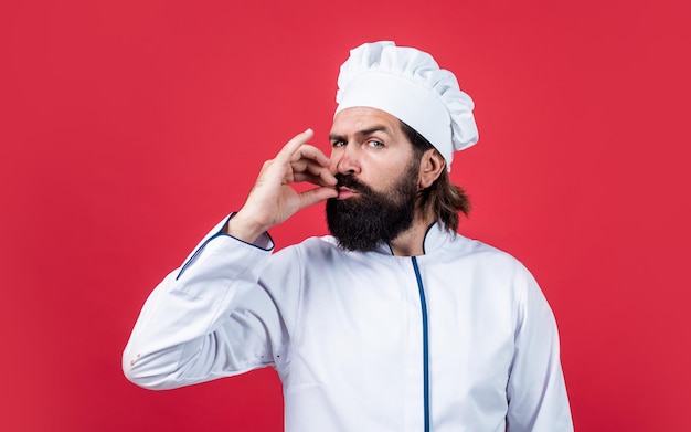 Confiado chef con barba y bigote en uniforme de cocinero muestra suspiro de excelencia sabor perfecto