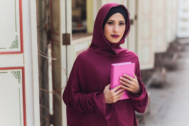 Confiado empresario árabe sonriendo y paseos de dubai arab business vumen hijab está en las calles contra los rascacielos de dubai, la mujer está vestida con una abaya negra