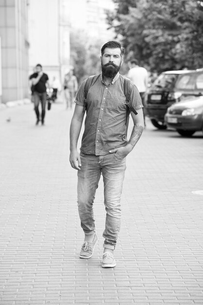 Confiado hombre brutal caminar calle Peluquero masculino cuidado brutal hipster con bigote concepto de aventura estilo urbano Comprometerse a viajar Hipster maduro con barba Hombre barbudo usar mochila