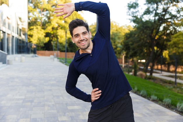 Foto confiado joven deportista haciendo ejercicios de estiramiento al aire libre