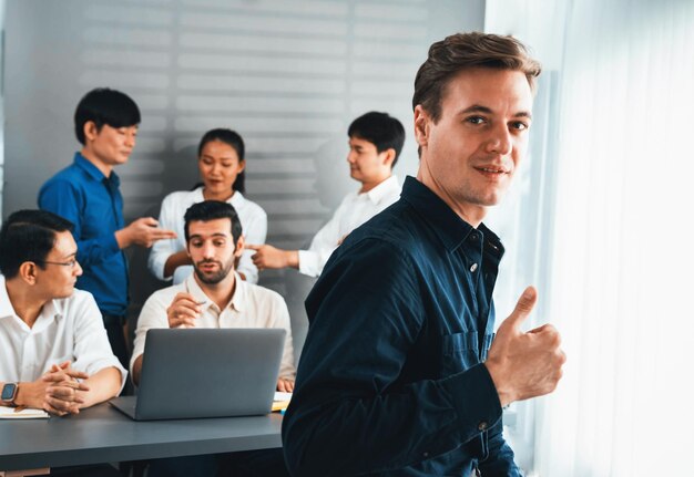 Confiança e sorriso feliz retrato de um empresário com o fundo de seu colega e equipe de negócios trabalhando em escritório Trabalhador de escritório trabalho em equipe e conceito positivo de local de trabalho Prudente