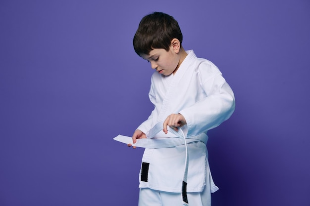 Confiante adolescente europeu veste quimono branco amarra um cinto em volta da cintura pronto para esportes de combate Aikido lutador Artes marciais orientais