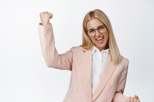 Confiante e motivada empresária gerente feminina cantando e comemorando triunfando e dizendo sim fundo branco