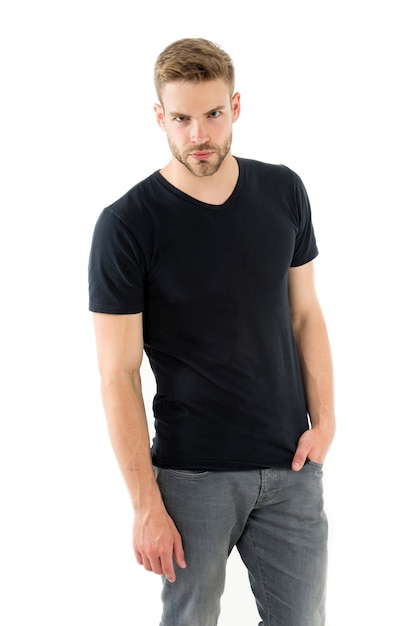 Confiante em seu estilo. Homem com fundo branco isolado de rosto estrito confiante de cerdas. Cara com barba por fazer colocar o bolso da mão parece bonito e confiante. Cara usa camisa preta casual. Simples, mas clássico.