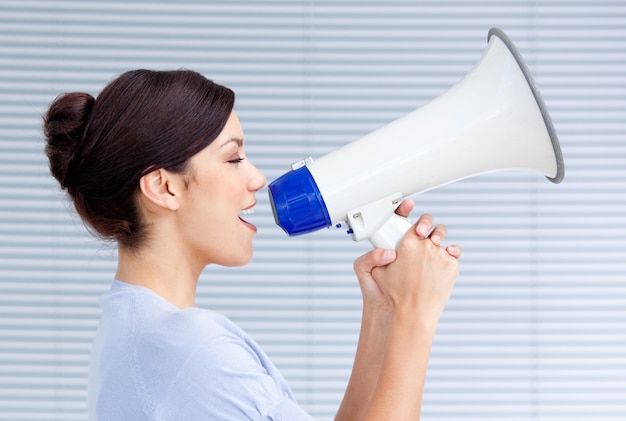 Foto confiante empresária gritando através de um megafone