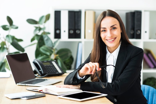 Confiante feliz jovem empresária sentado na mesa do escritório