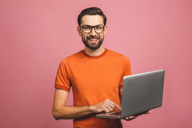 Foto confiante jovem bonito em casual segurando laptop e sorrindo em pé.