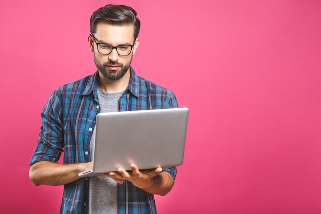 Confiante jovem bonito na camisa segurando laptop e sorrindo