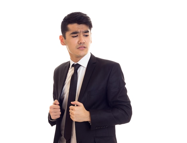 Confiante jovem com cabelo preto na camisa branca e terno preto com gravata preta sobre fundo branco