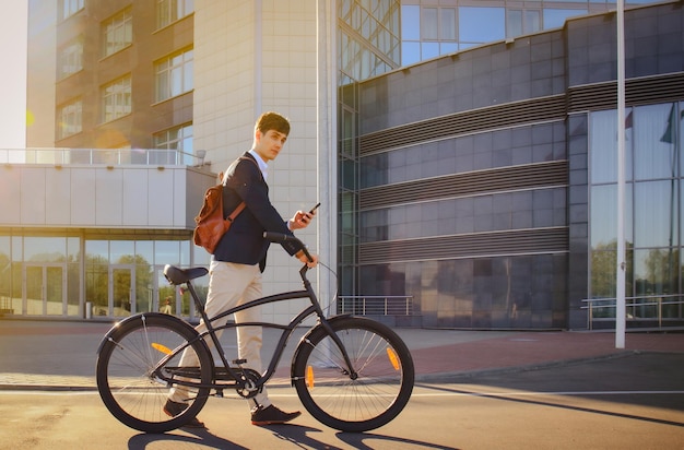 Confiante jovem empresário andando com bicicleta na rua da cidade