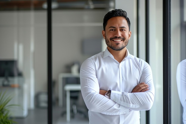 Confiante rico feliz jovem latino homem de negócios de pé no escritório braços cruzados retrato sorrindo