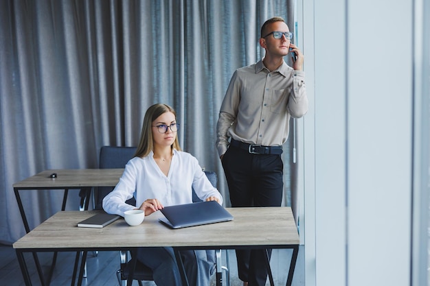 Confiantes colegas homens e mulheres em roupas casuais elegantes estão discutindo um projeto no local de trabalho desfrutando de amizade corporativa parceiros felizes estão falando sobre redes de escritório em um telefone celular