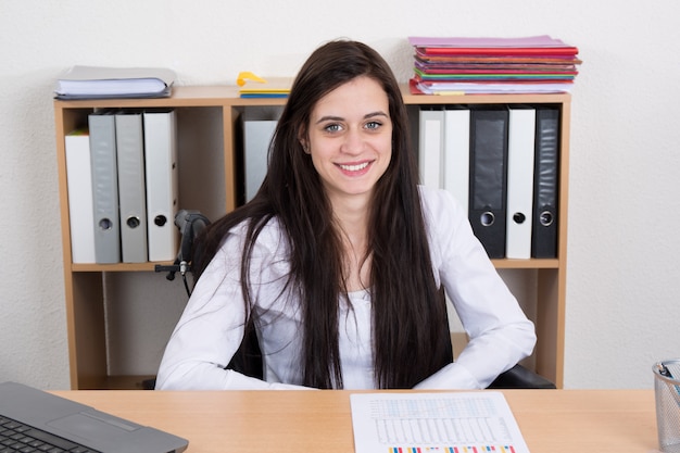 Foto confianza empresaria feliz en silla de ruedas trabajando en la oficina