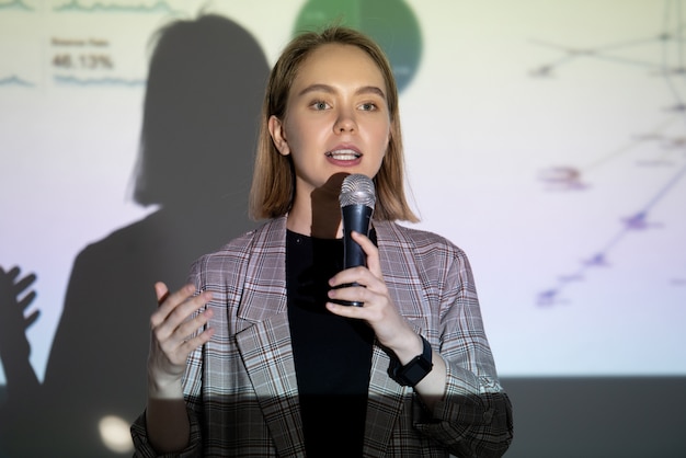 Confianza empresaria joven hablando sobre su éxito en el micrófono en la conferencia de emprendimiento